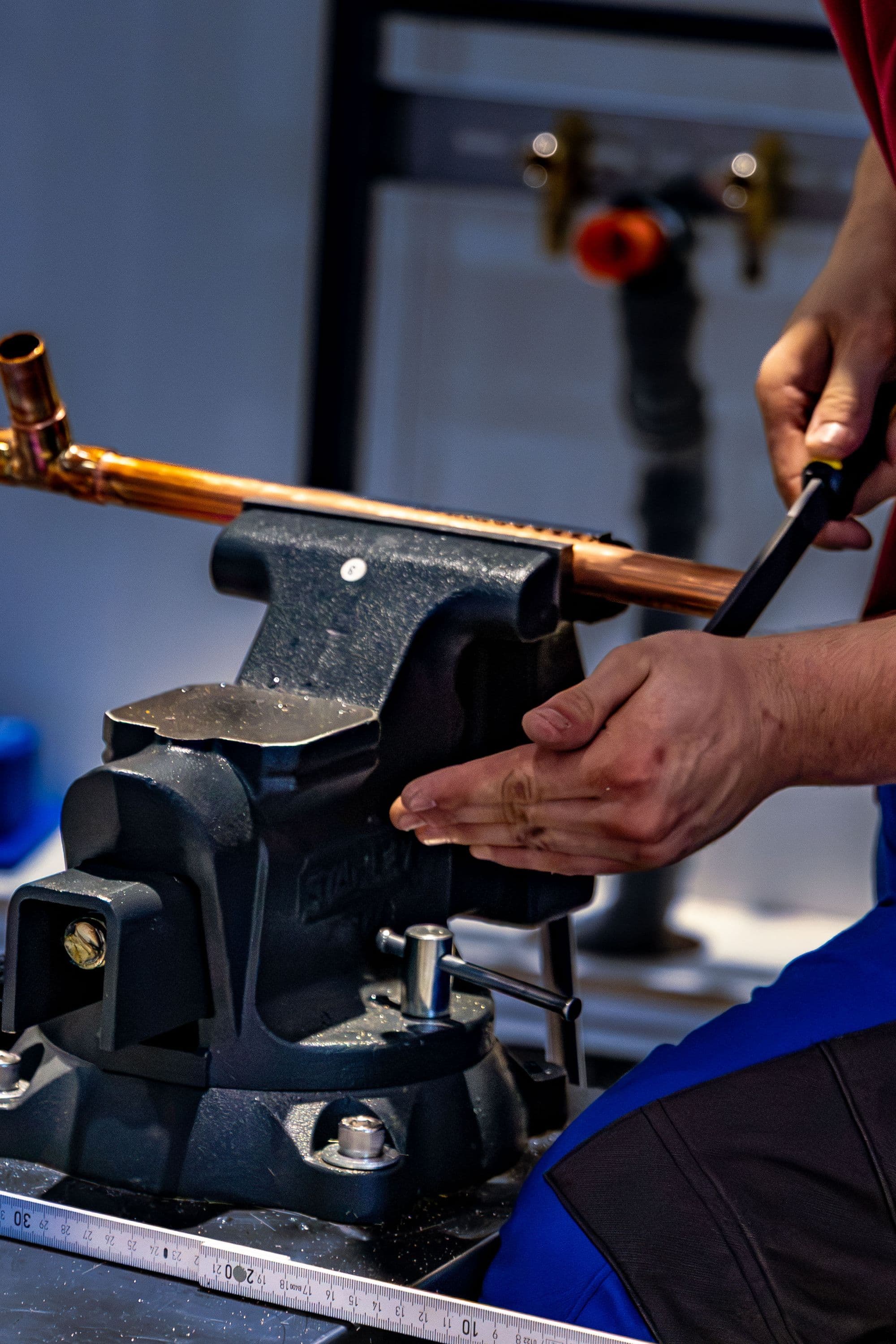 A plumber setting a length of copper pipe in a vise